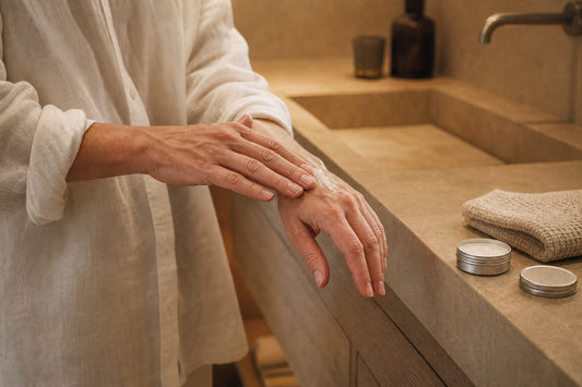 Hände verteilen etwas Handcreme, daneben eine Dose und ein Handtuch